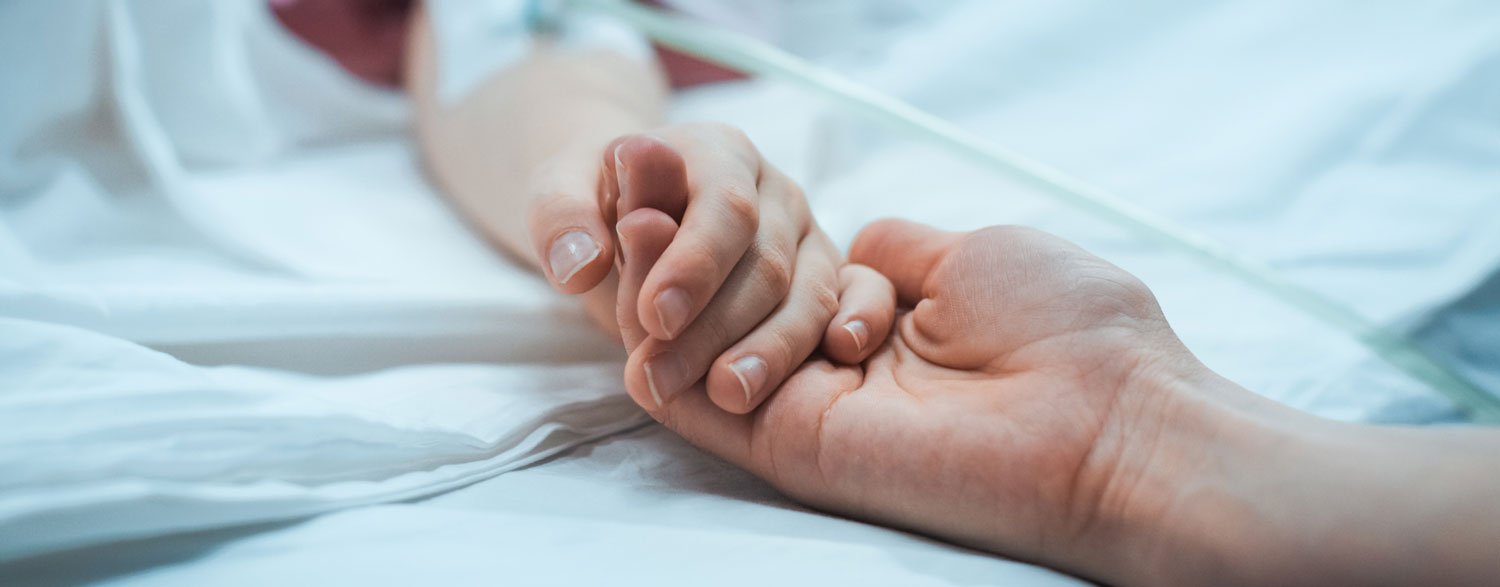 Close up of adult holding sick childs hand.