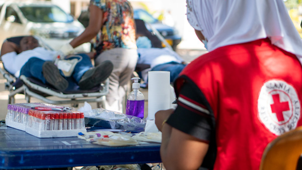 A woman prepares blood collection equipment at an outdoor blood donor centre in Africa